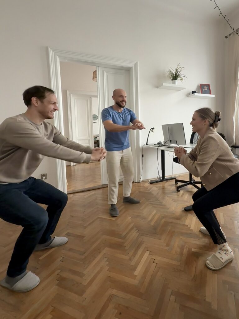 Two men and a woman are squatting at the primehammer office, as stretches and breaks between calls are helpful for mental health.