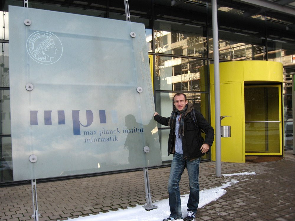 Young David standing in front of the Max Planck Institut Informatik plate.